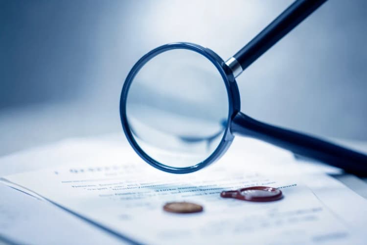 Uma lupa examinando um contrato com selos de cera, em um fundo de madeira escura.