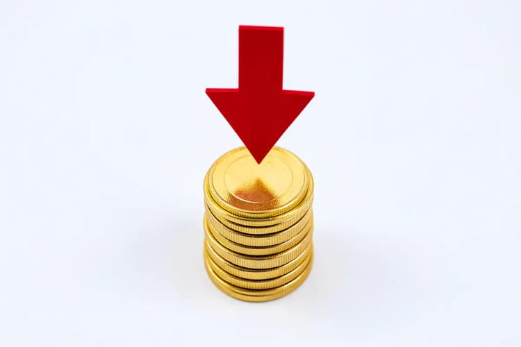 Uma pilha de moedas de ouro com uma seta vermelha apontando para baixo, em um fundo branco.